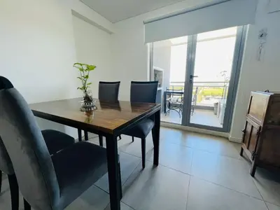 a dining room table and chairs with a view of a balcony at DEPARTAMENTO DE 1 DORMITORIO CON VISTA A LAS SIERRAS Av Colon 5034 in Cordoba