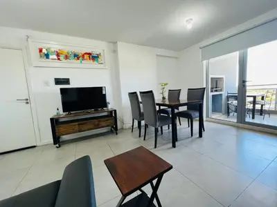 a living room with a television and a table and chairs at DEPARTAMENTO DE 1 DORMITORIO CON VISTA A LAS SIERRAS Av Colon 5034 in Cordoba