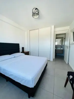 a bedroom with a white bed and a bathroom at DEPARTAMENTO DE 1 DORMITORIO CON VISTA A LAS SIERRAS Av Colon 5034 in Cordoba