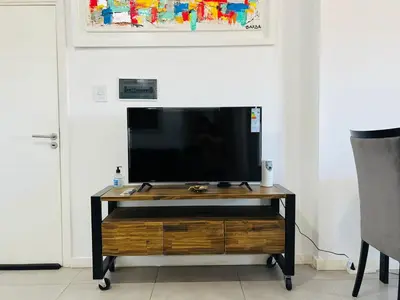 a flat screen tv sitting on top of a wooden entertainment center at DEPARTAMENTO DE 1 DORMITORIO CON VISTA A LAS SIERRAS Av Colon 5034 in Cordoba