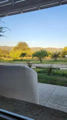 a white bench in front of a view of a field at La Pasionaria casa de sierras in Santa Rosa de Calamuchita