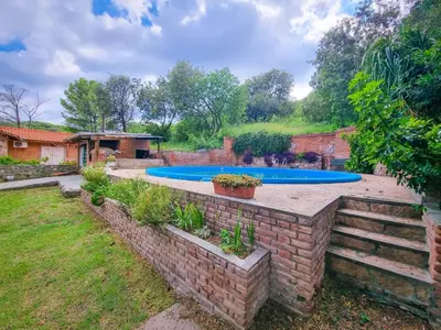a swimming pool in a yard with a brick wall at El Solar de los Pájaros in Merlo