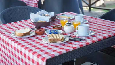 a red and white checkered table with food and drinks at Winds Hill Resort & Spa in Merlo