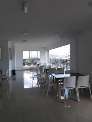 a dining room with tables and white chairs and windows at Edificio Leonardo departamento 16 in Villa Carlos Paz