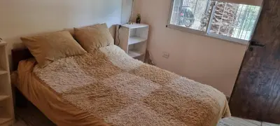 a bedroom with a bed with a brown blanket and a window at Departamento Costa Paz in Villa Carlos Paz