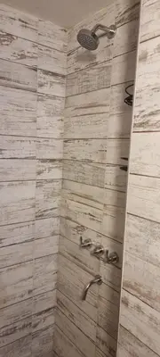 a bathroom with a shower with a wooden wall at Departamento Costa Paz in Villa Carlos Paz