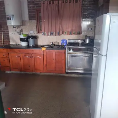 a kitchen with wooden cabinets and a stainless steel refrigerator at Pecas house in Mina Clavero