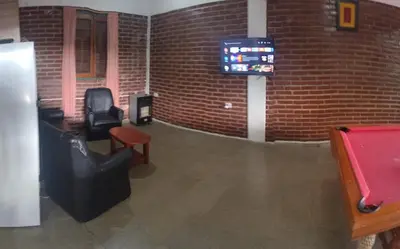 a room with two chairs and a tv on a brick wall at Pecas house in Mina Clavero