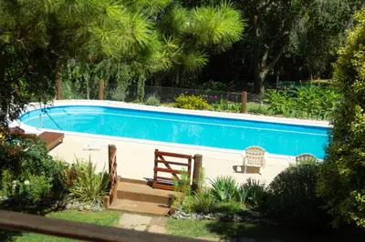 a swimming pool with a bench and a chair in a yard at Cabañas Mirador de la Bahia in Villa Ciudad Parque