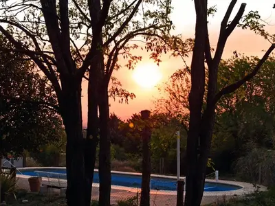 a sunset over a swimming pool with trees at Cabañas Mirador de la Bahia in Villa Ciudad Parque