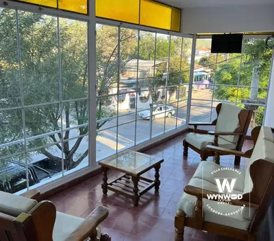 a waiting room with chairs and a table and large windows at Wynwood Extreme Hostel in Villa Carlos Paz