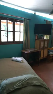 a bedroom with a bed and a desk and windows at Monoambiente Elegante in Los Hornillos