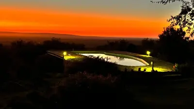 a sunset with a pool on a hill with lights at El Lugar in Travesía