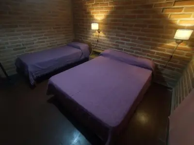 two beds in a room with a brick wall at Sierras Alojamiento Departamentos in Mina Clavero
