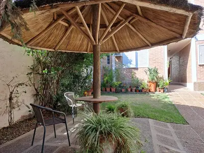 a patio with a table and chairs under a wooden umbrella at PARQUE DEL SIERRAS in Alta Gracia