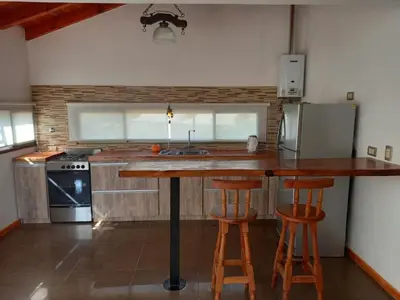 a kitchen with a counter and two bar stools at Sueños de Montaña in Villa Yacanto