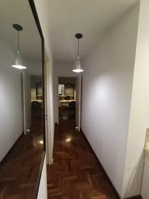 a hallway with white walls and wood floors and two lights at ERA Residential Apartament in Cordoba