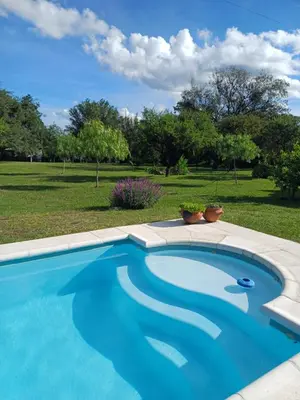 a blue swimming pool with a field in the background at Las Guardia in Cortaderas