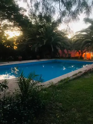 a blue swimming pool with trees in the background at La carolina in Villa de Las Rosas