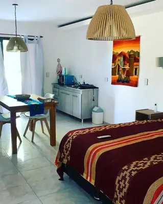 a bedroom with a bed and a table and a kitchen at La carolina in Villa de Las Rosas