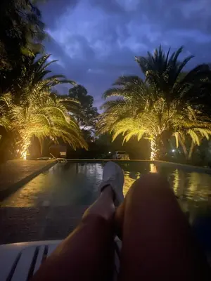 a person sitting on a bench next to a swimming pool at La carolina in Villa de Las Rosas