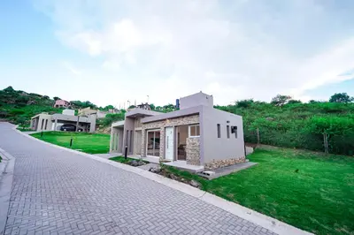 a small white house on a green lawn at Sunset Village in Villa Carlos Paz