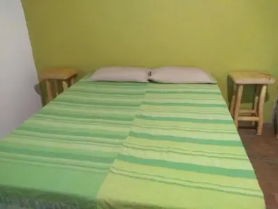 a green bedroom with a bed with two chairs at Casa alma verde in Luyaba