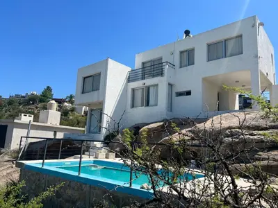 a house with a swimming pool in front of it at Duplex en plena montaña in Villa Carlos Paz