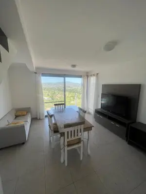 a living room with a table and a couch and a television at Duplex en plena montaña in Villa Carlos Paz
