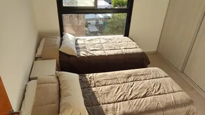 two beds in a room with a couch and a window at departamento de dos dormitorios in Cordoba