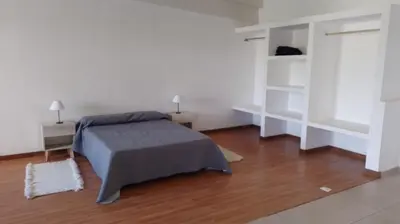 a bedroom with a bed and white walls and wood floors at Lake360 Dto 51 in Villa Carlos Paz