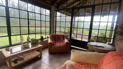 a living room with a couch and a table and windows at Posada Sausalito in Santa Rosa de Calamuchita