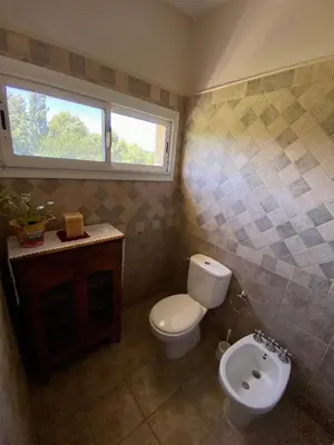 a bathroom with a toilet and a sink and a window at Posada Sausalito in Santa Rosa de Calamuchita