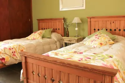a bedroom with two beds and a table with a lamp at Posada Sausalito in Santa Rosa de Calamuchita