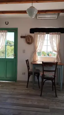 a room with a table and chairs and a green door at La Flor del Camino Posada in Tanti