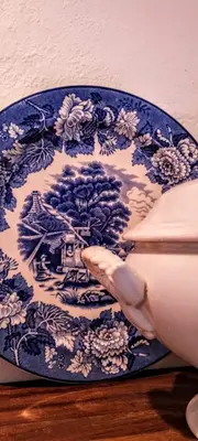 a hand is holding a blue and white plate at La Flor del Camino Posada in Tanti