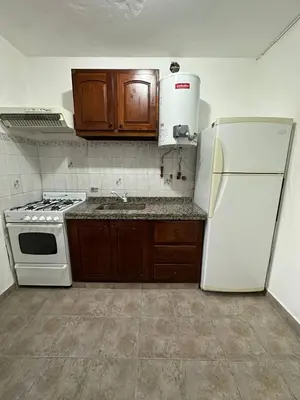 a kitchen with a white refrigerator and wooden cabinets at Encantos del Valle - Santa Rosa de Calamuchita in Santa Rosa de Calamuchita