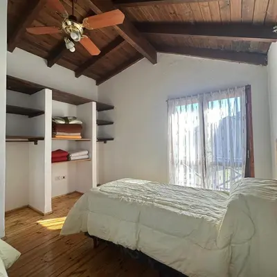a bedroom with a bed with a ceiling fan and a window at Encantos del Valle - Santa Rosa de Calamuchita in Santa Rosa de Calamuchita