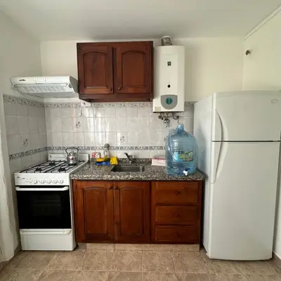 a kitchen with a white refrigerator and a sink at Encantos del Valle - Santa Rosa de Calamuchita in Santa Rosa de Calamuchita