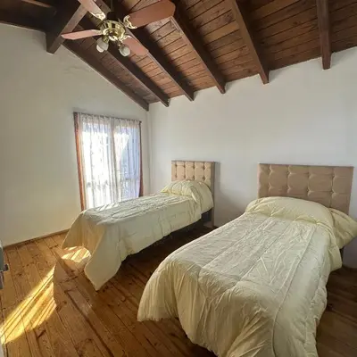 a bedroom with two beds and a ceiling fan at Encantos del Valle - Santa Rosa de Calamuchita in Santa Rosa de Calamuchita