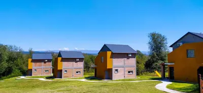 a row of houses on a grassy field at Cabañas Madre Sierra in Santa Rosa de Calamuchita
