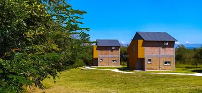 two brick buildings in a field with trees at Cabañas Madre Sierra in Santa Rosa de Calamuchita