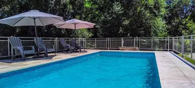 a swimming pool with two umbrellas and two chairs at Cabañas Madre Sierra in Santa Rosa de Calamuchita