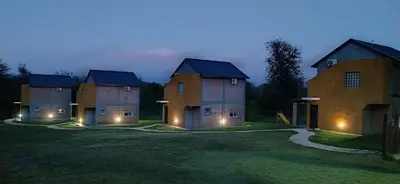 a group of three brick buildings with lights on them at Cabañas Madre Sierra in Santa Rosa de Calamuchita