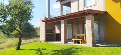 a house with a table on the side of it at Cabañas Madre Sierra in Santa Rosa de Calamuchita