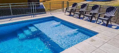 a swimming pool with two chairs and a swimming pool at Cabañas Madre Sierra in Santa Rosa de Calamuchita