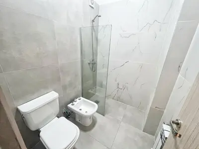 a bathroom with a toilet and a glass shower at Edificio Darwin in Villa Carlos Paz