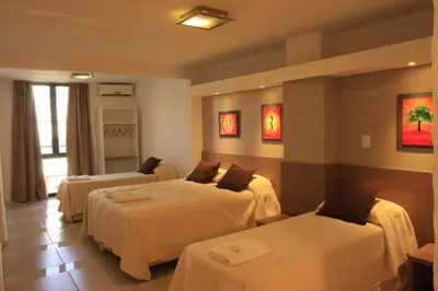 a hotel room with two beds and two tables at HOTEL CONTINENTAL PLAZA in Villa Carlos Paz