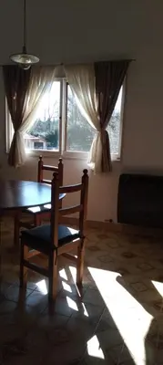 a dining room with a table and a chair in front of a window at Casa/ Villa General Belgrano in Villa General Belgrano