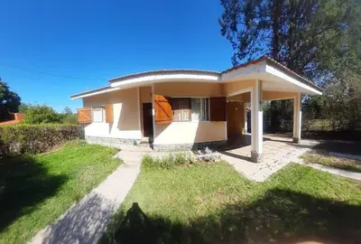 a small white house with a grassy yard at Casa/ Villa General Belgrano in Villa General Belgrano